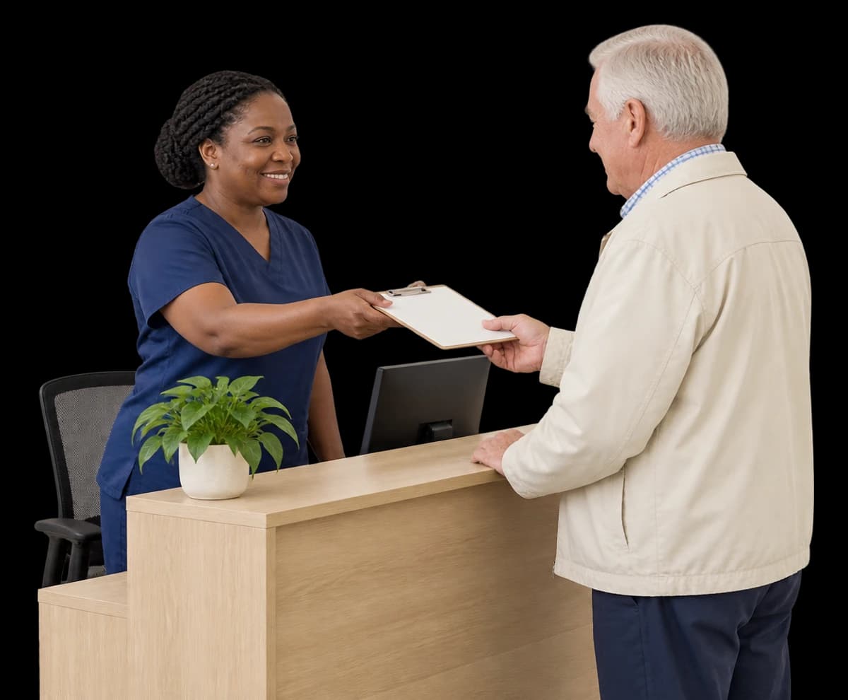 A clinic coordinator hands a clipboard to a patient across a reception counter.