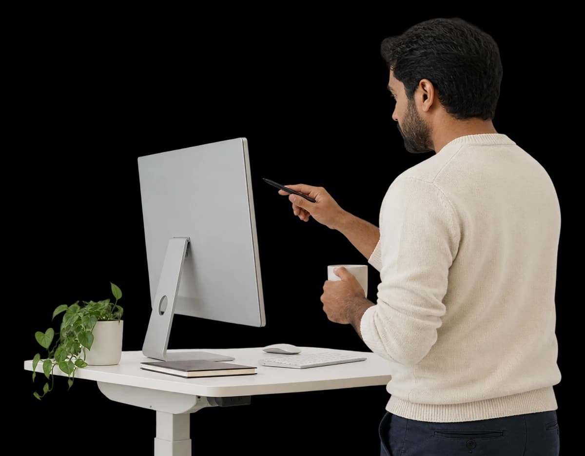 A data scientist stands at a desk, pointing at a monitor with a pen.