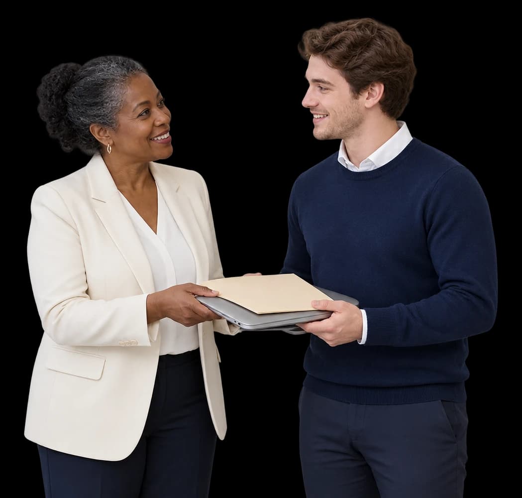 An HR manager hands a laptop and welcome folder to a new hire.