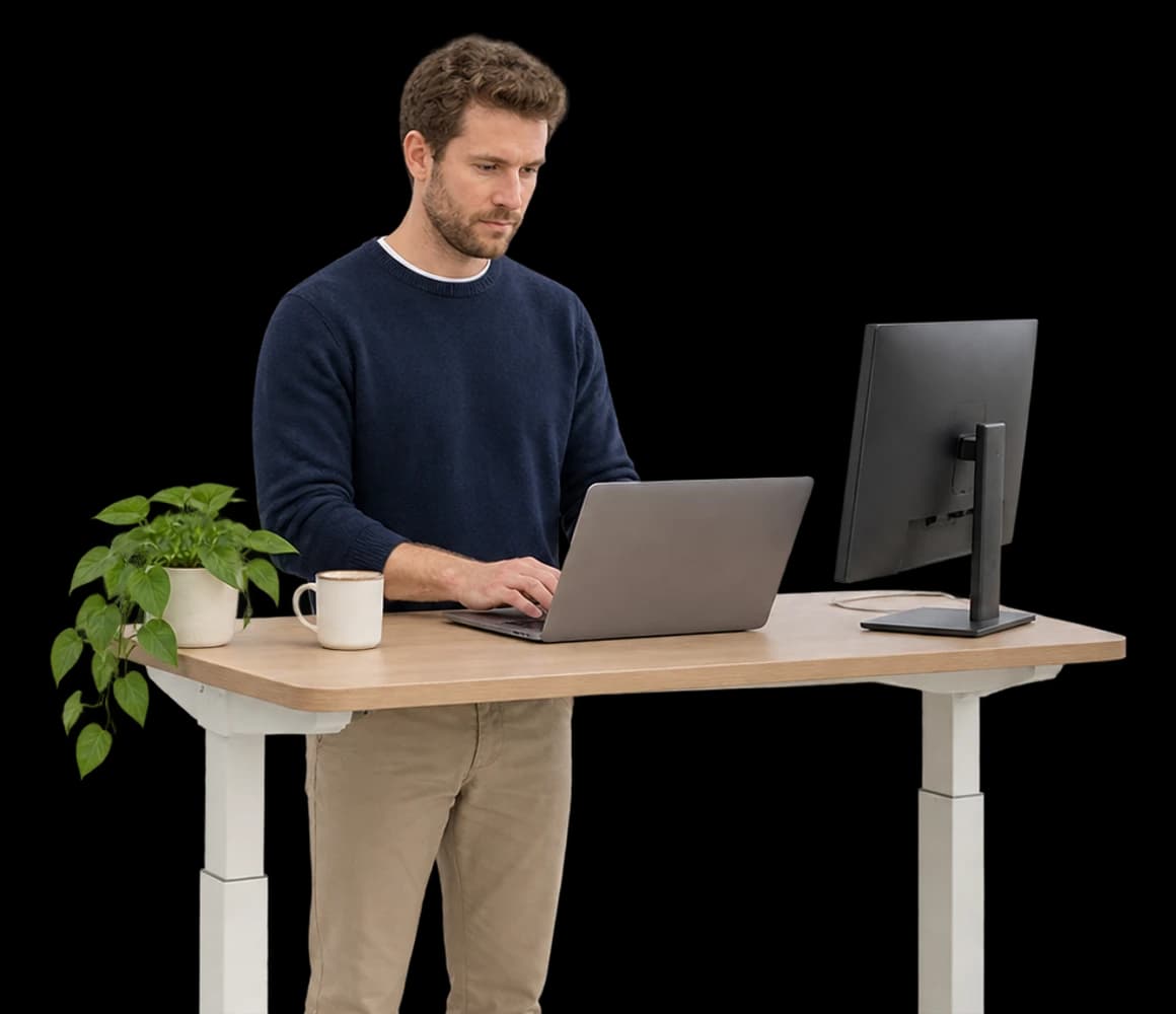 A product engineer types on a laptop at a standing desk.